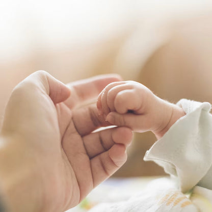 A mother holding the hand of her baby